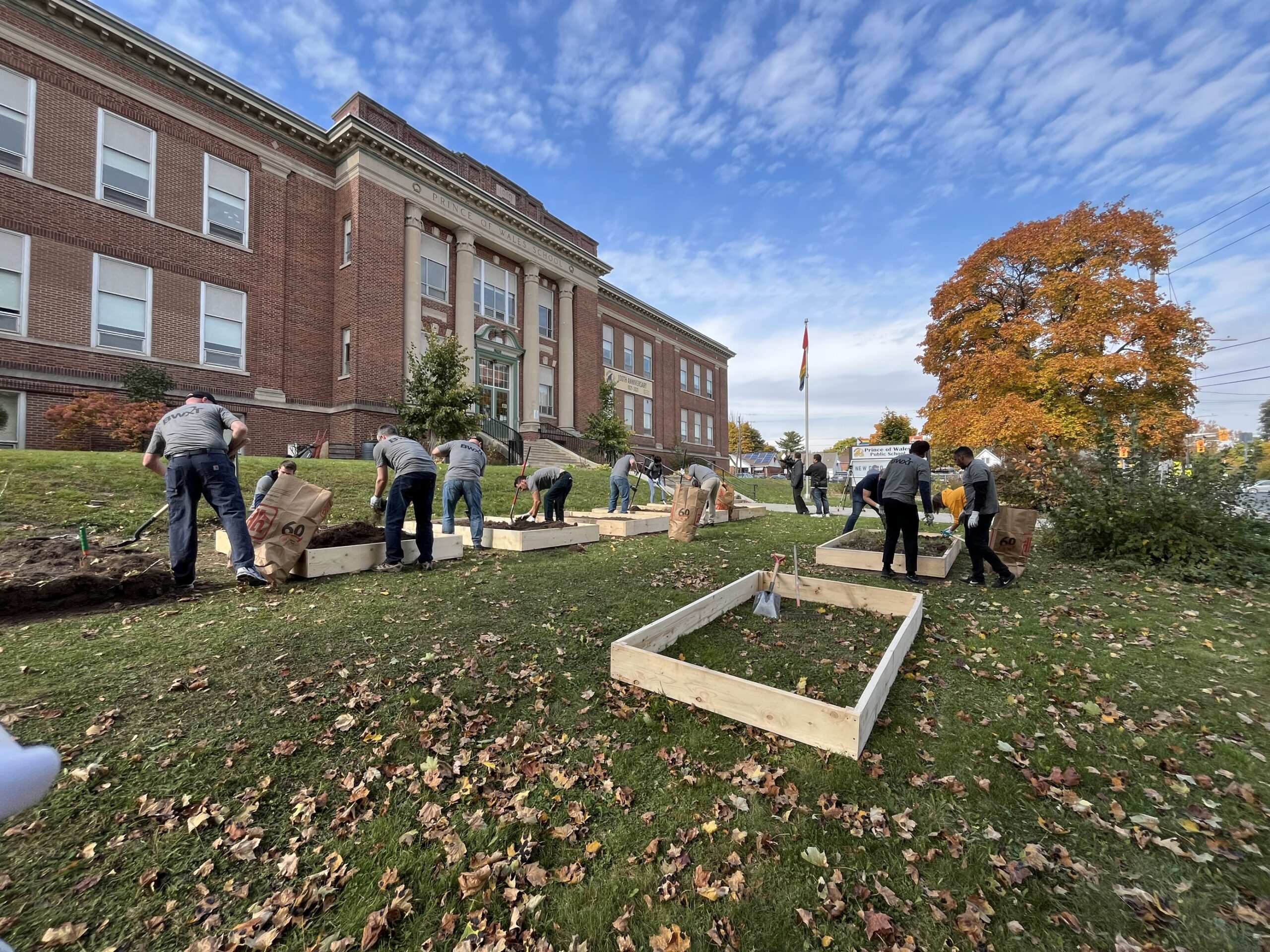 BWXT Prince of Wales Public School volunteering project employees clearing land for planting flowers landscaping in front of school building